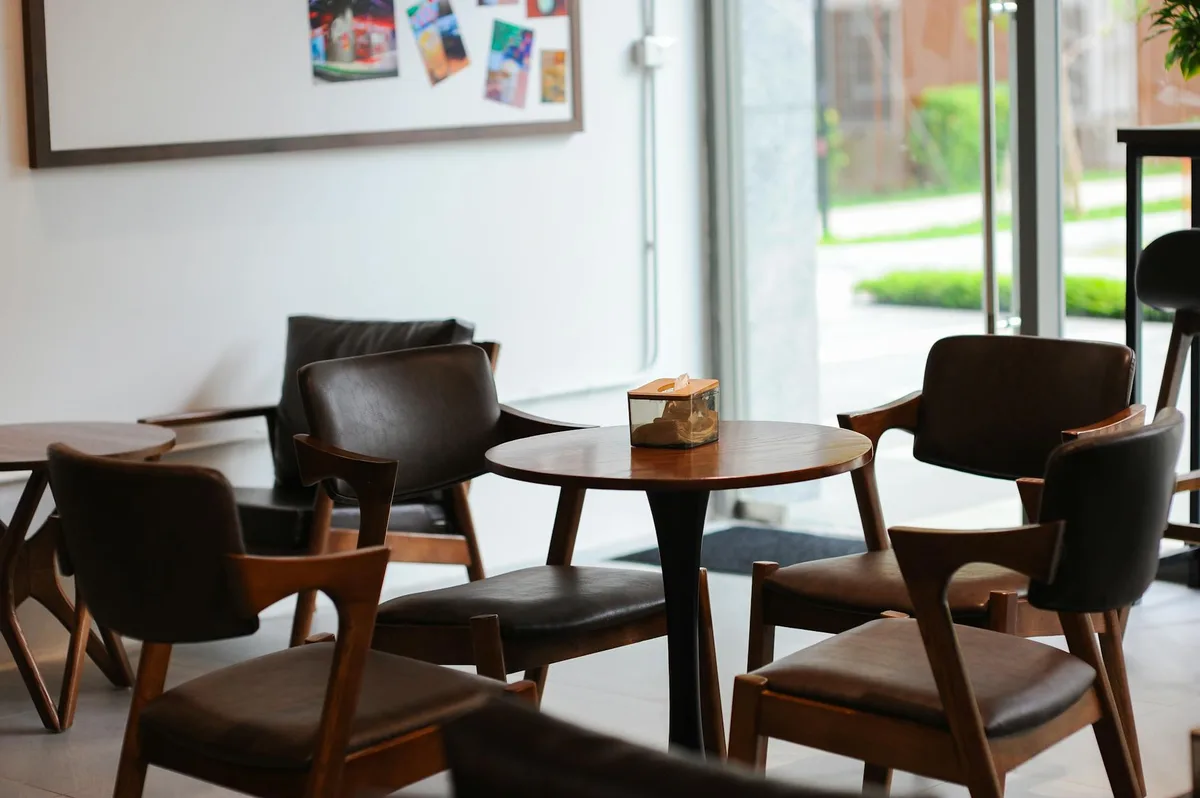 Warm and inviting coffee shop interior in Hà Nội, Việt Nam with modern wooden furniture and large windows.