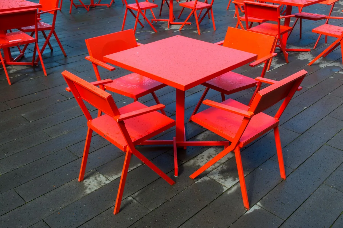 Vibrant red chairs and tables on a terrace with a wooden floor at Bergen aan Zee.
